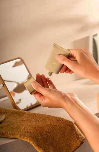 Person applying a skincare product to their hand with a mirror in the background