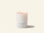 A lit white scented candle in a matte white glass jar with the brand name CANOPY HOME and scent name FRENCH PEAR & VELVET printed on the front, set against a warm off-white background.