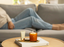 Person relaxing on a couch with a candle and skincare product on a coffee table