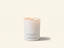 A lit white scented candle in a matte white glass jar with the brand name CANOPY HOME and scent name LAVENDER & WILD MOSS printed on the front, set against a warm off-white background.