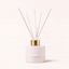 A reed diffuser bottle by Canopy Home in the scent 'Frenchtown & Meliot', featuring a matte white cylindrical bottle with a shiny gold collar and six white reeds, set against a warm off-white background.