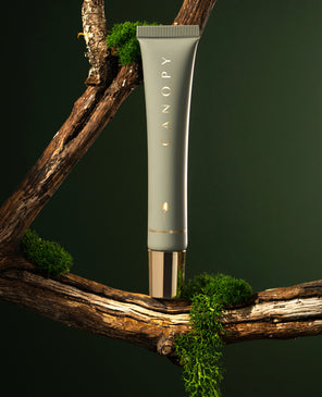 Skincare tube labeled 'Canopy' on a branch with greenery
